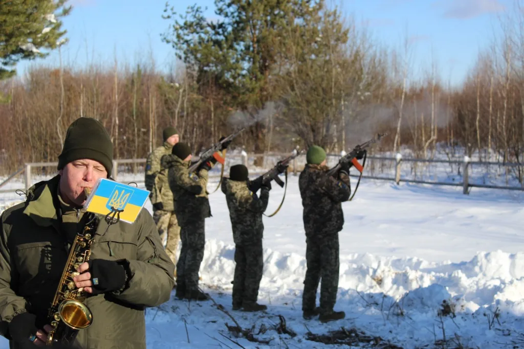 Військові стріляють салют, музикант грає саксофон