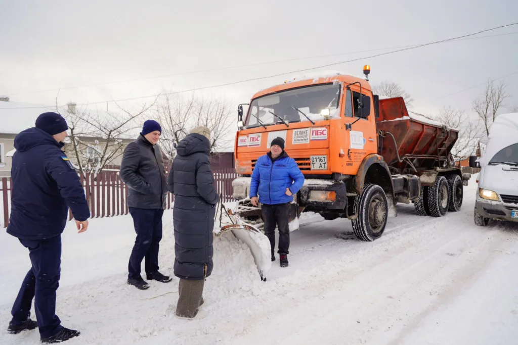 Люди біля снігоприбиральної машини на зимовій дорозі