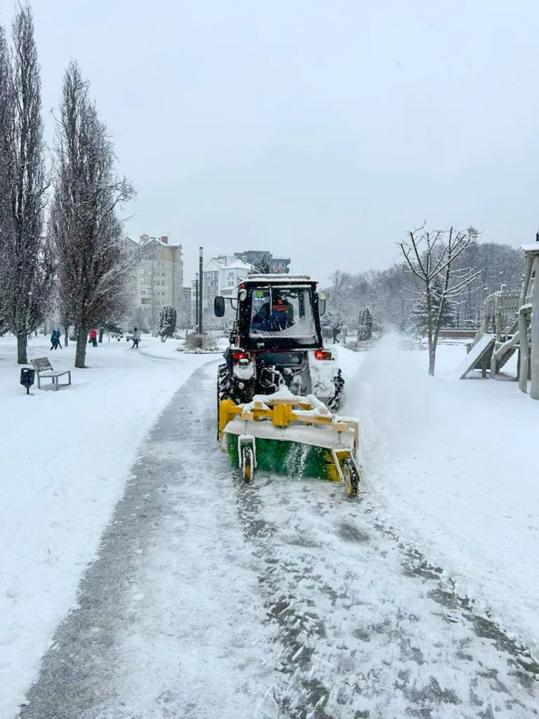 Трактор прибирає сніг на парковій доріжці