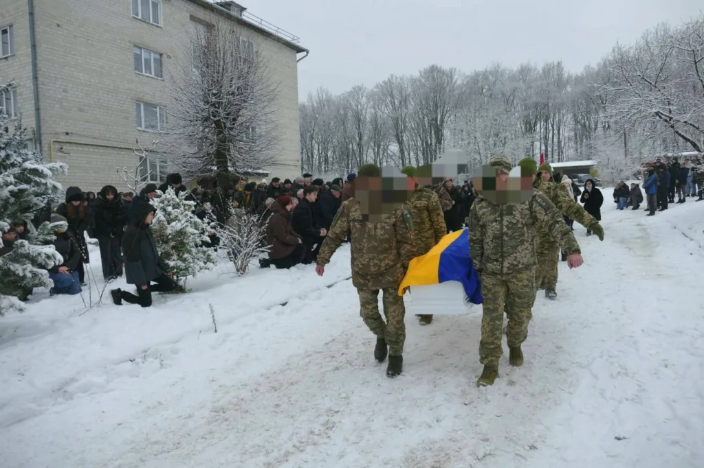 Військові несуть труну з українським прапором узимку