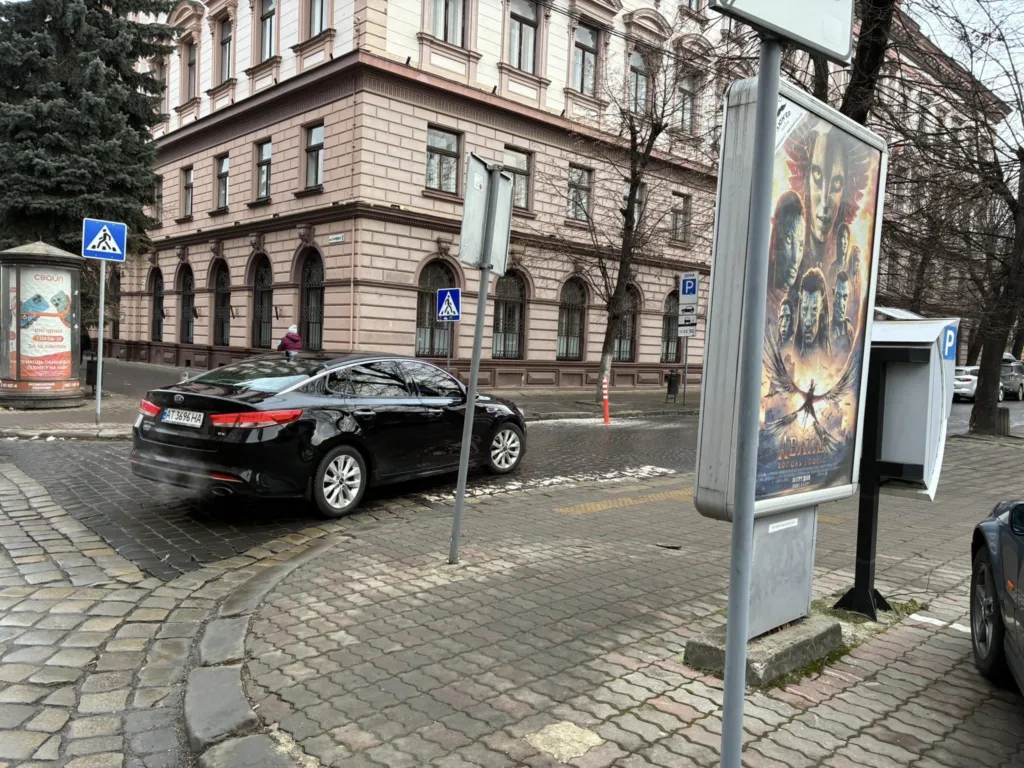 Чорне авто біля вулиці та рекламного щита