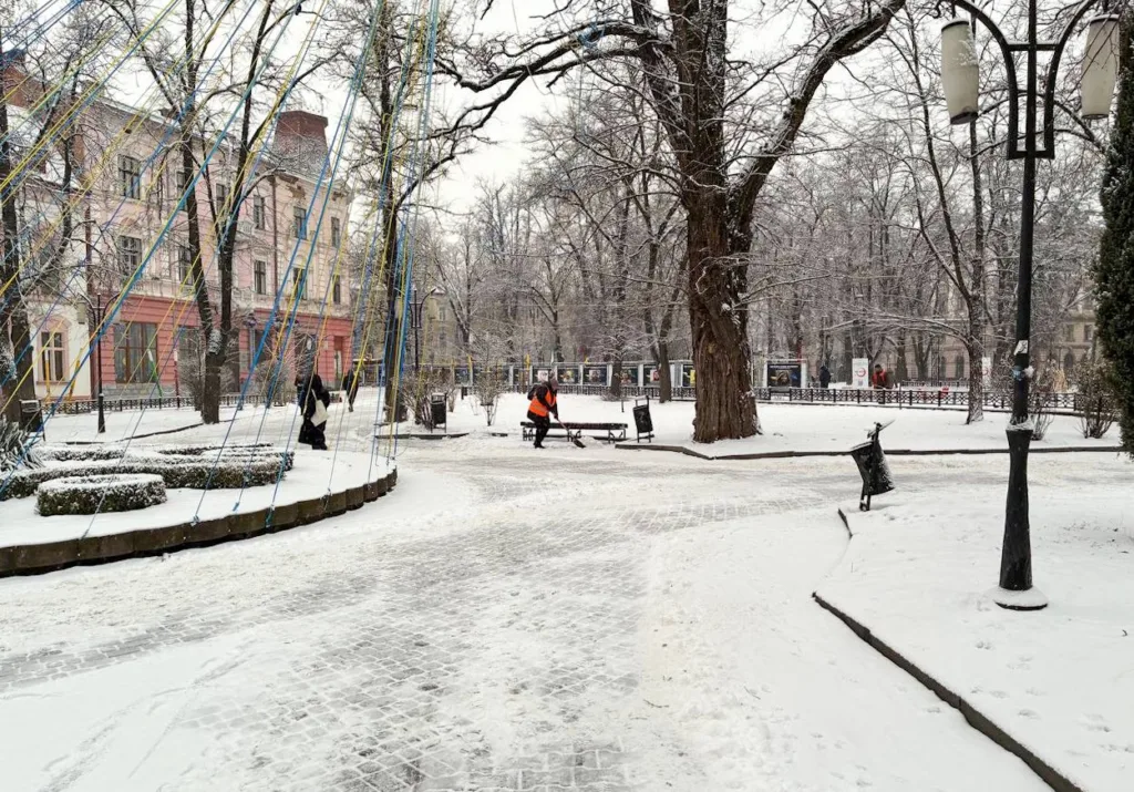 Зимовий міський парк зі снігом і перехожими