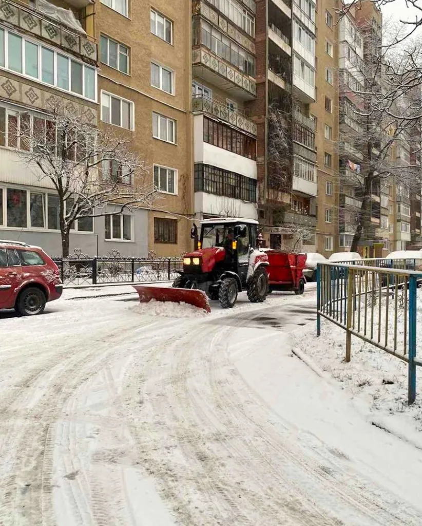 Трактор очищає сніг перед житловим будинком