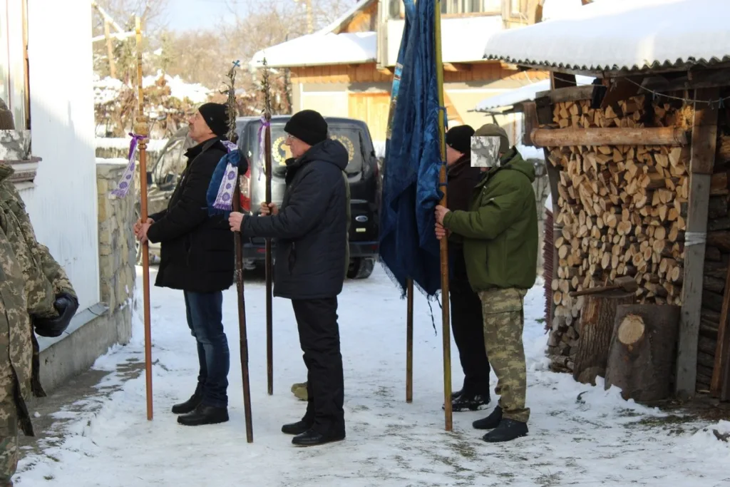 Люди з прапорами стоять на засніженому подвір’ї