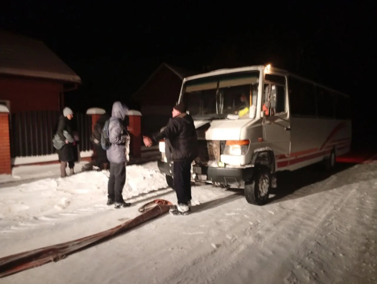 Люди біля автобуса на зимовій засніженій дорозі