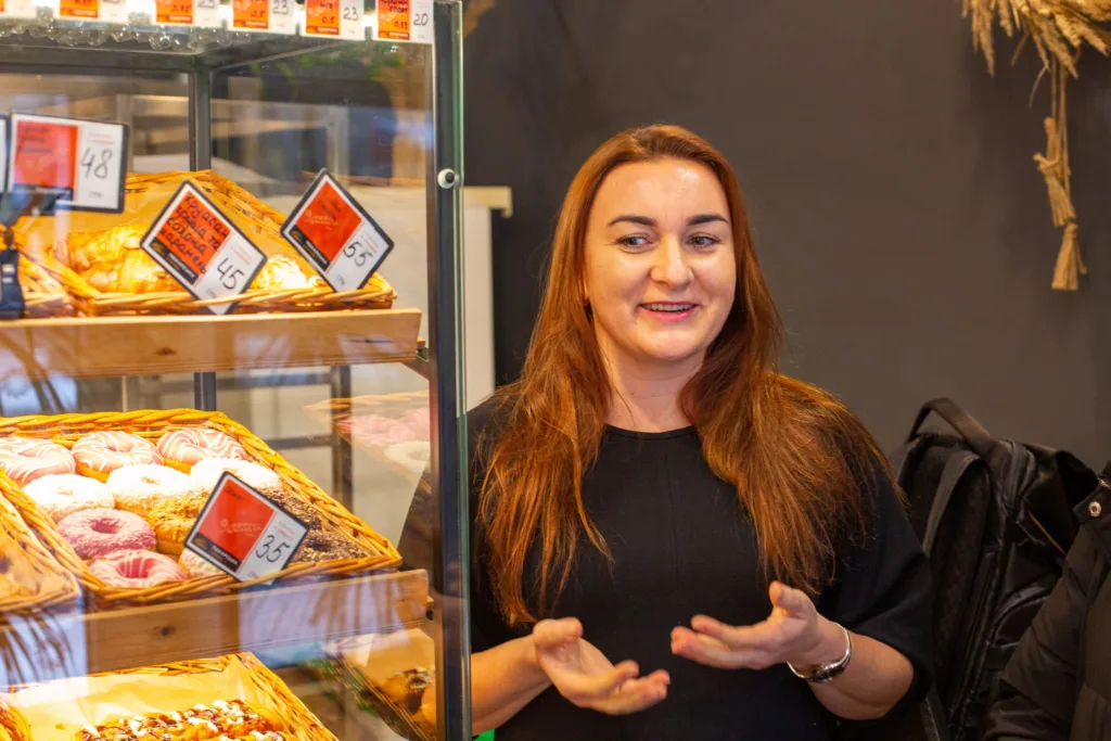 Жінка біля вітрини з випічкою у пекарні