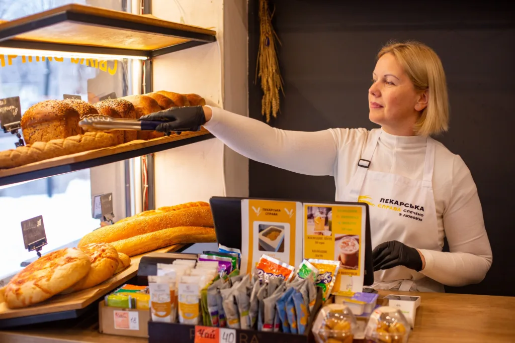 Пекарка викладає свіжий хліб на полицю