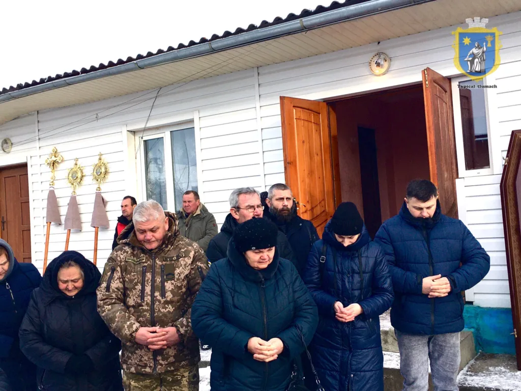 Люди моляться перед церквою взимку