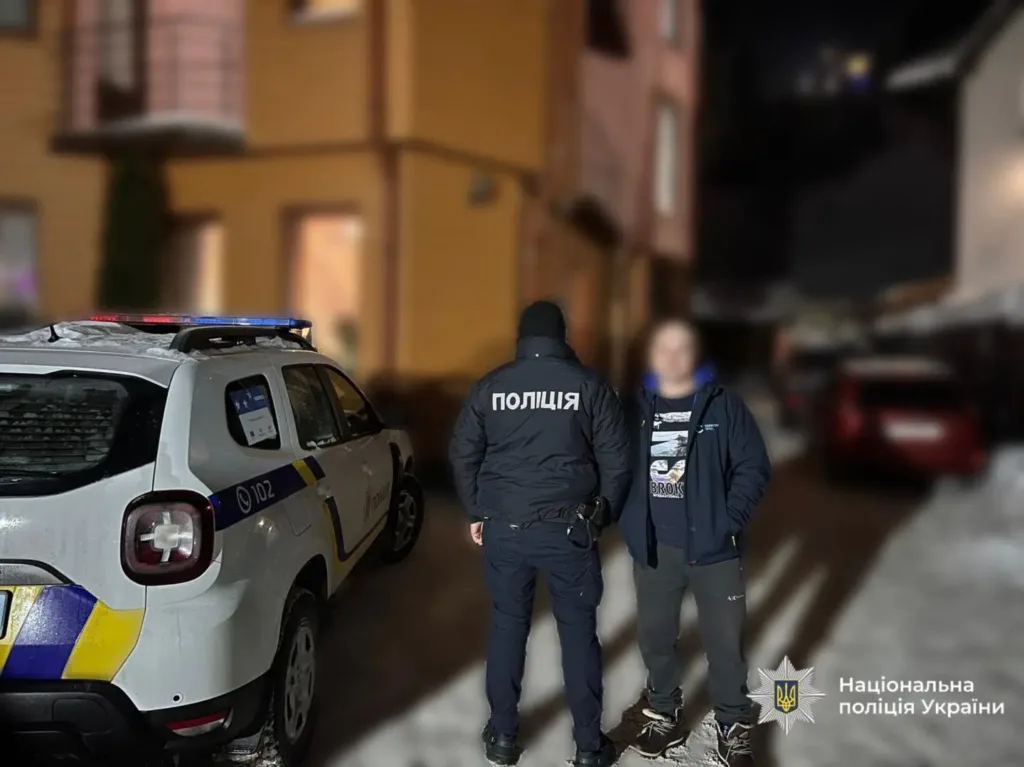 Поліцейський поруч із підозрюваним біля патрульного авто