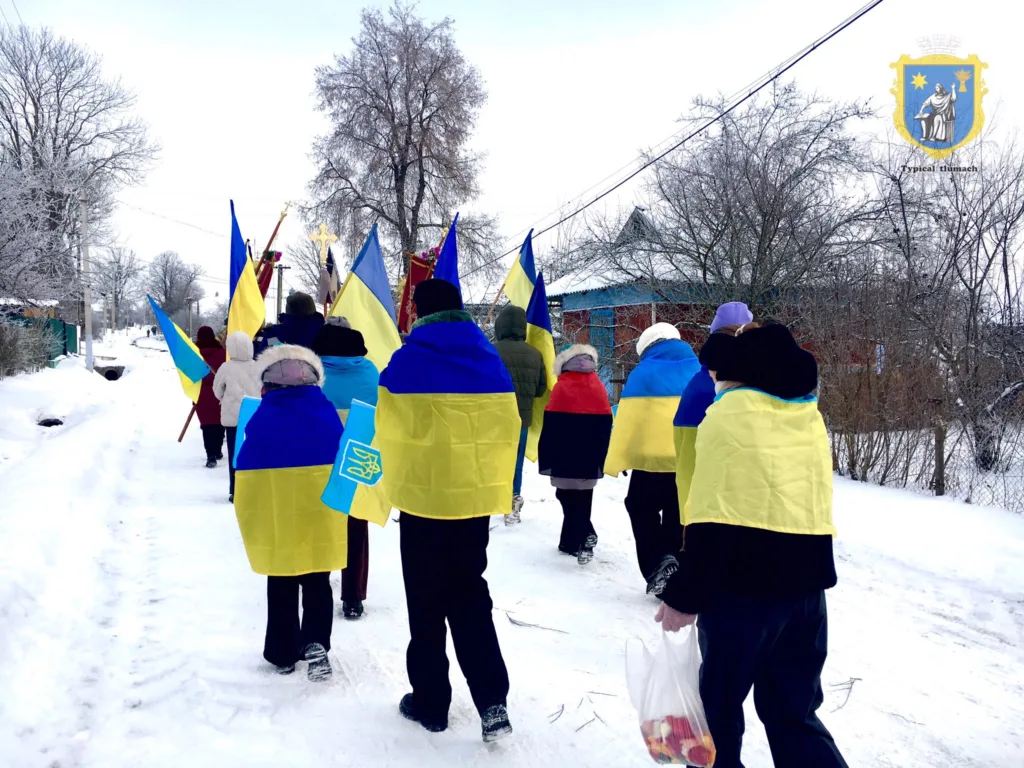 Люди з прапорами України йдуть зимовою вулицею