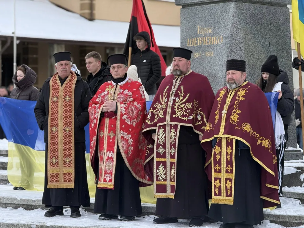 Священики біля пам’ятника Тарасу Шевченку з прапорами