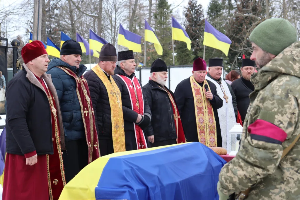 Священники моляться на похороні воїна України