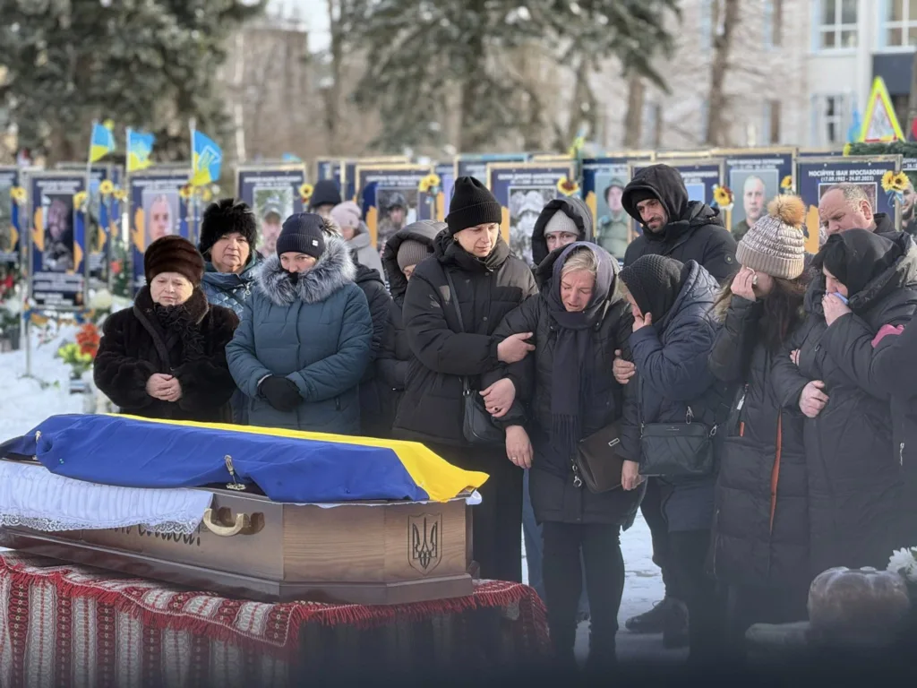 Прощання з воїном біля труни, накритої прапором України