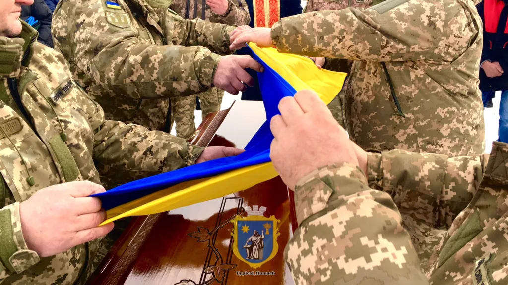 Військові складають український прапор на труні