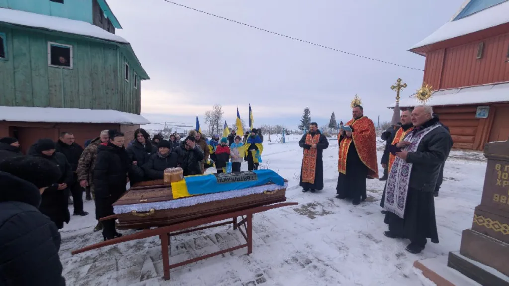 Похоронна церемонія з українськими прапорами на снігу