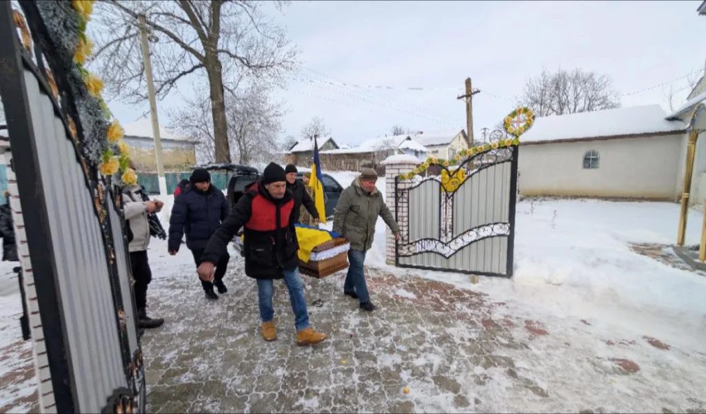 Похорон у зимовому селі з українським прапором