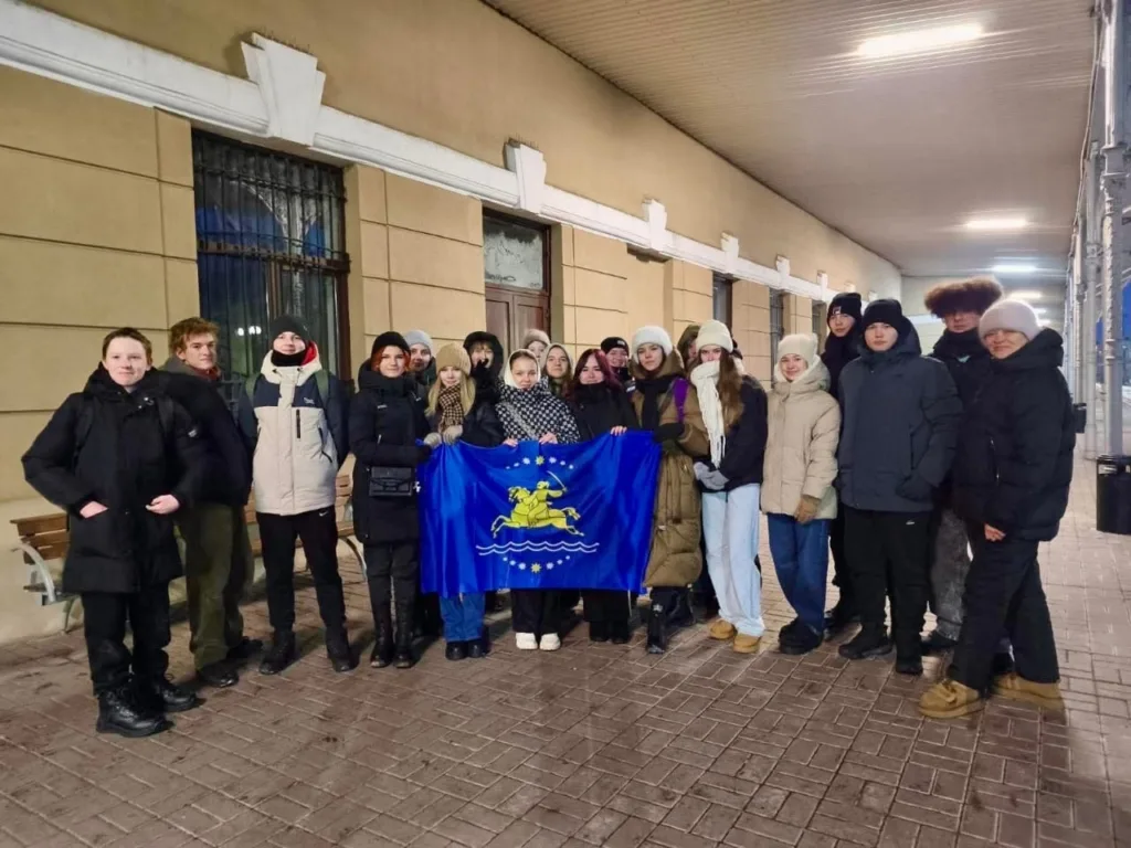 Група молоді тримає синій прапор на вокзалі