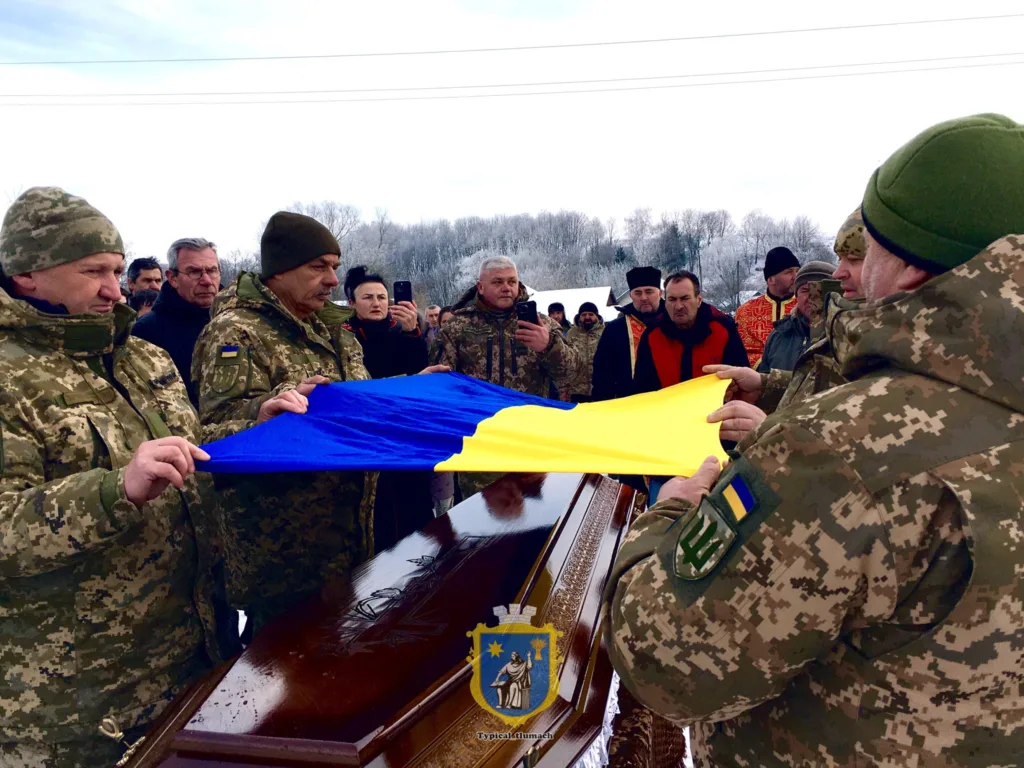 Військові накривають труну українським прапором