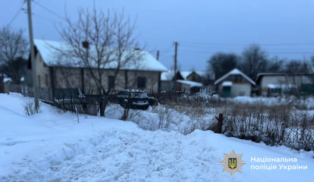 Засніжене село з будинками та припаркованим автомобілем