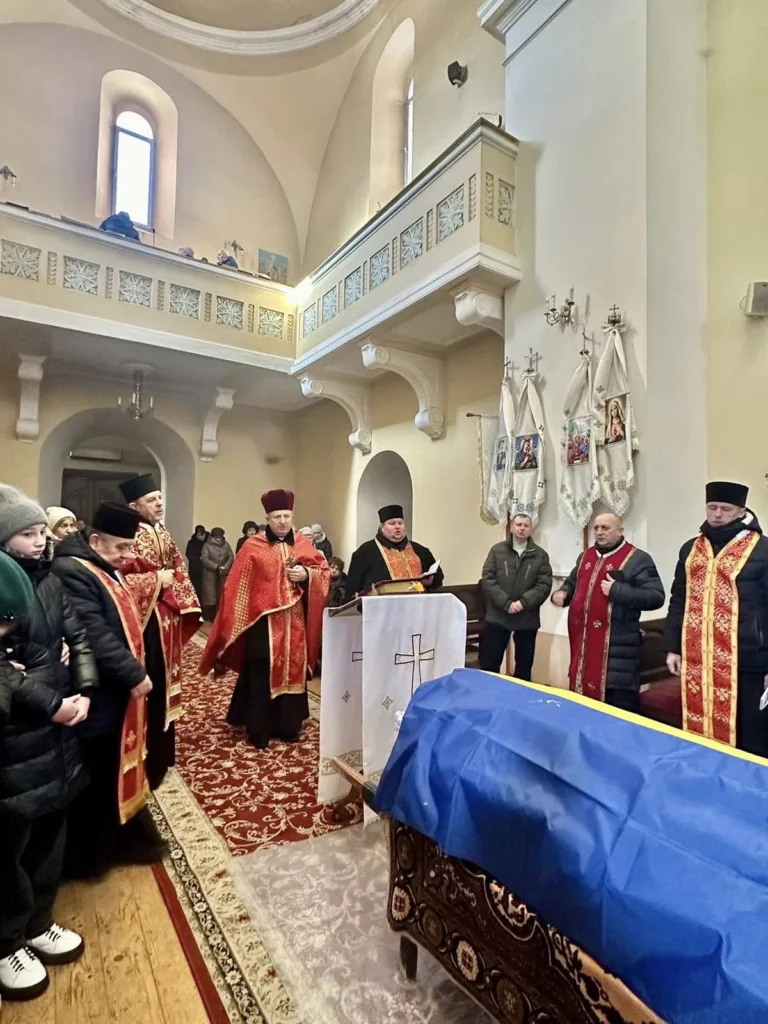 Поминальна служба в церкві з труною під прапором