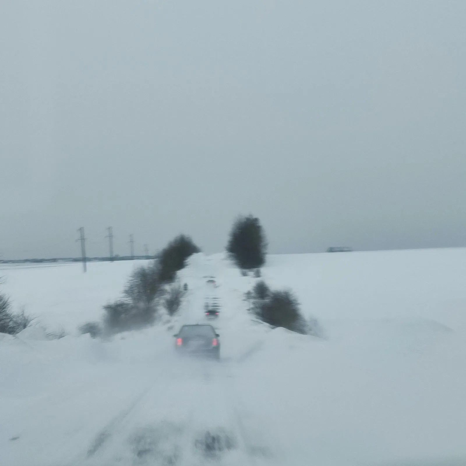 Автомобіль їде засніженою дорогою серед полів