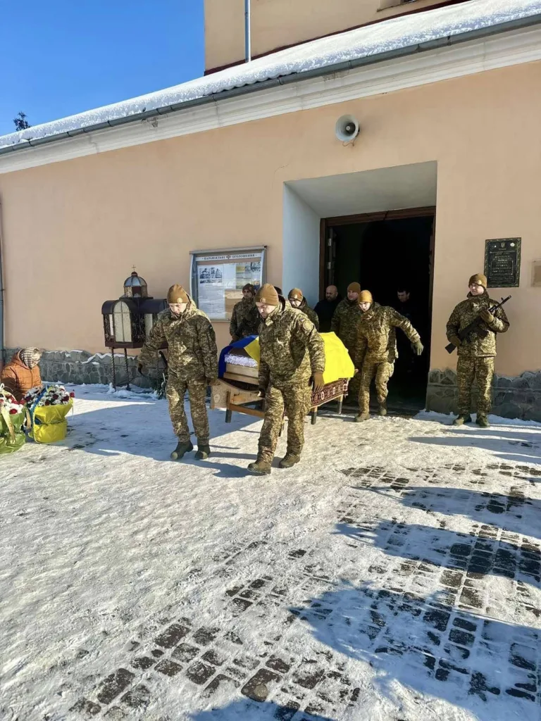 Військові виносять труну, накриту українським прапором