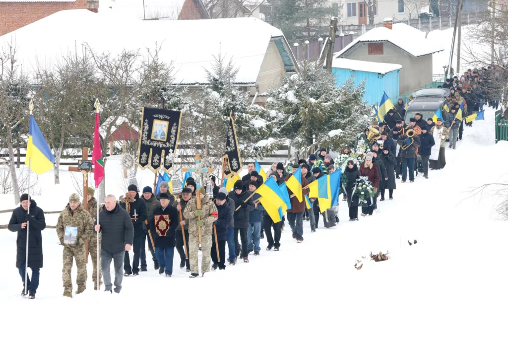 Похоронна процесія з українськими прапорами взимку
