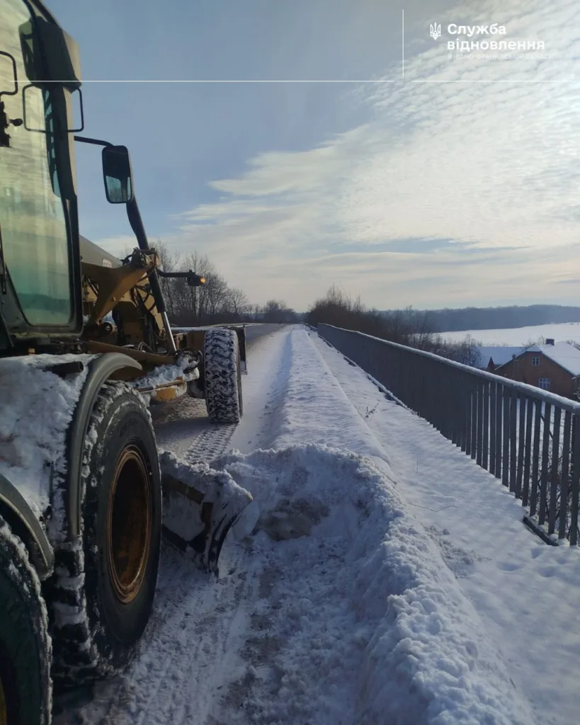Грейдер розчищає сніг на зимовій дорозі