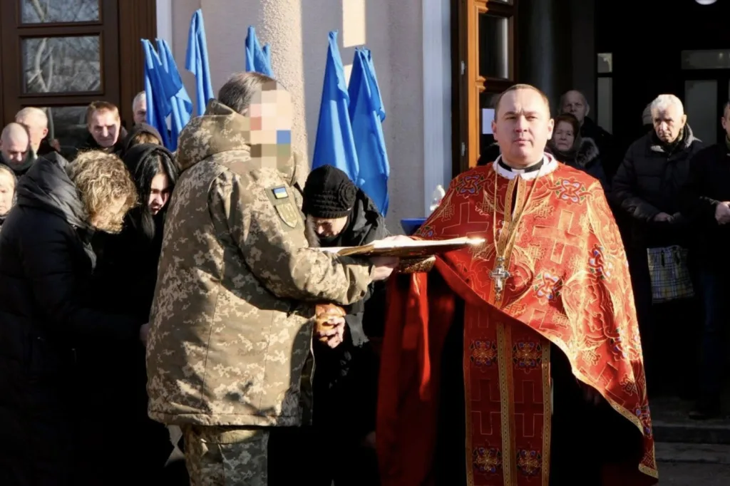 Священник проводить церемонію біля військового