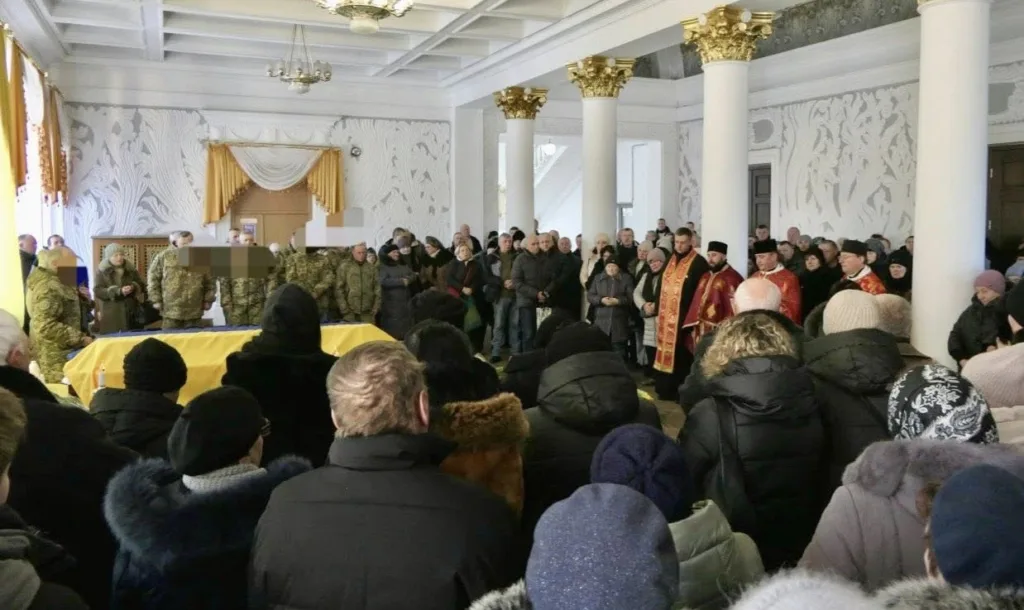 Прощання з військовим у залі зі священниками