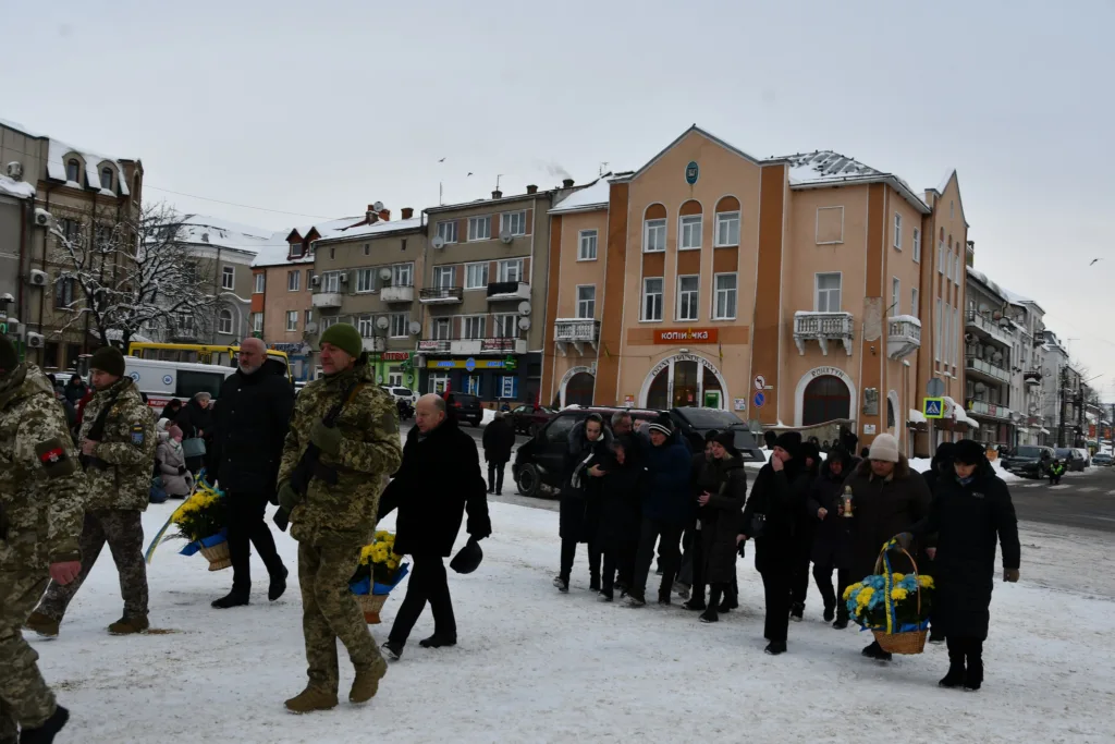 Військові та люди несуть квіти зимовим містом