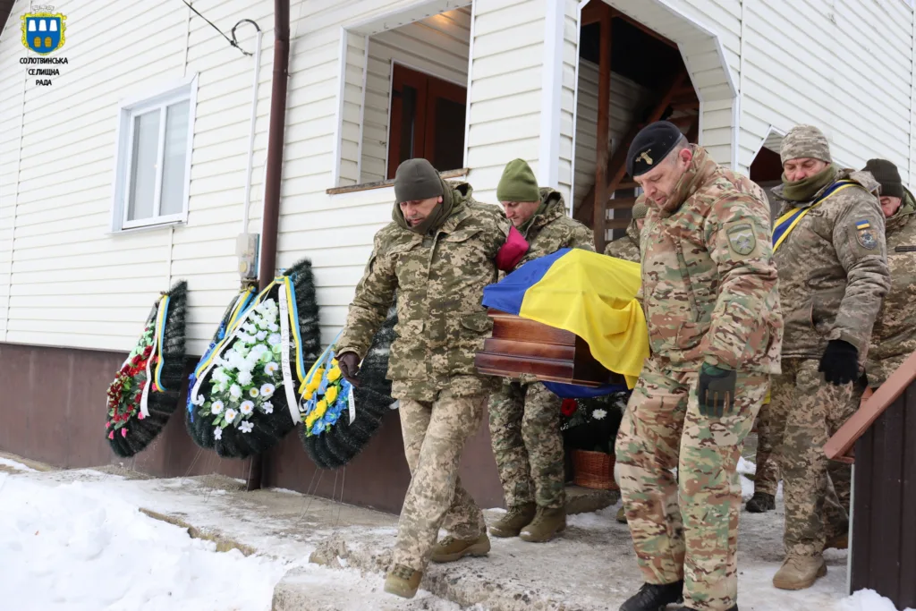 Військові несуть труну, накриту прапором України