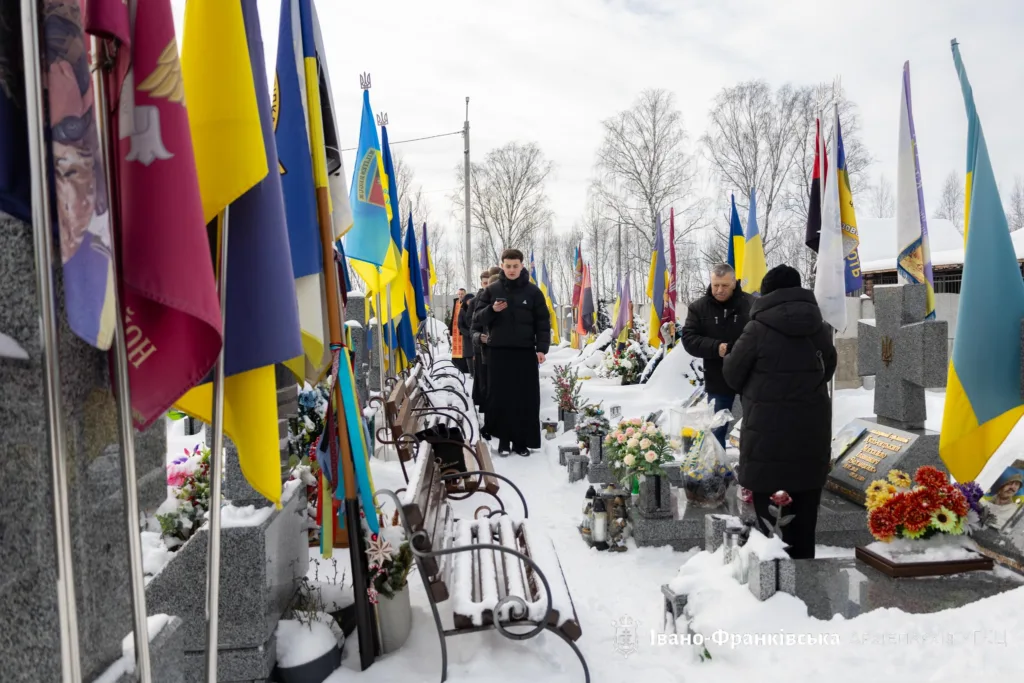 Люди вшановують полеглих героїв на цвинтарі взимку