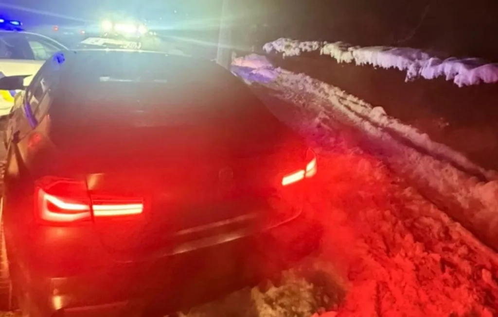 Поліцейська машина на засніженій нічній дорозі