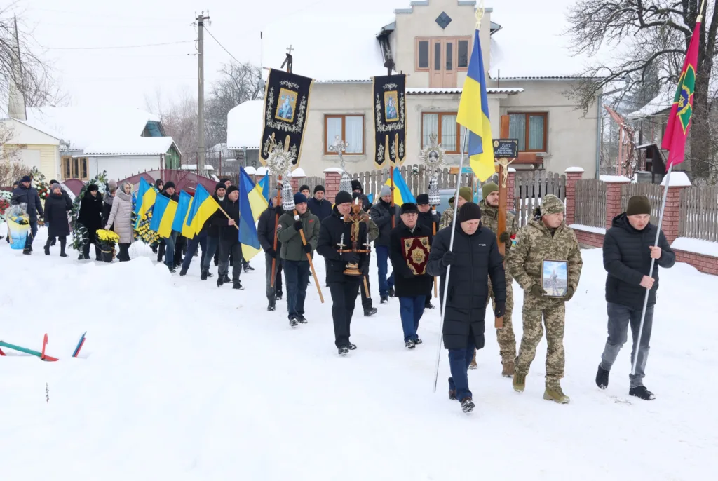 Похоронна процесія з українськими прапорами взимку