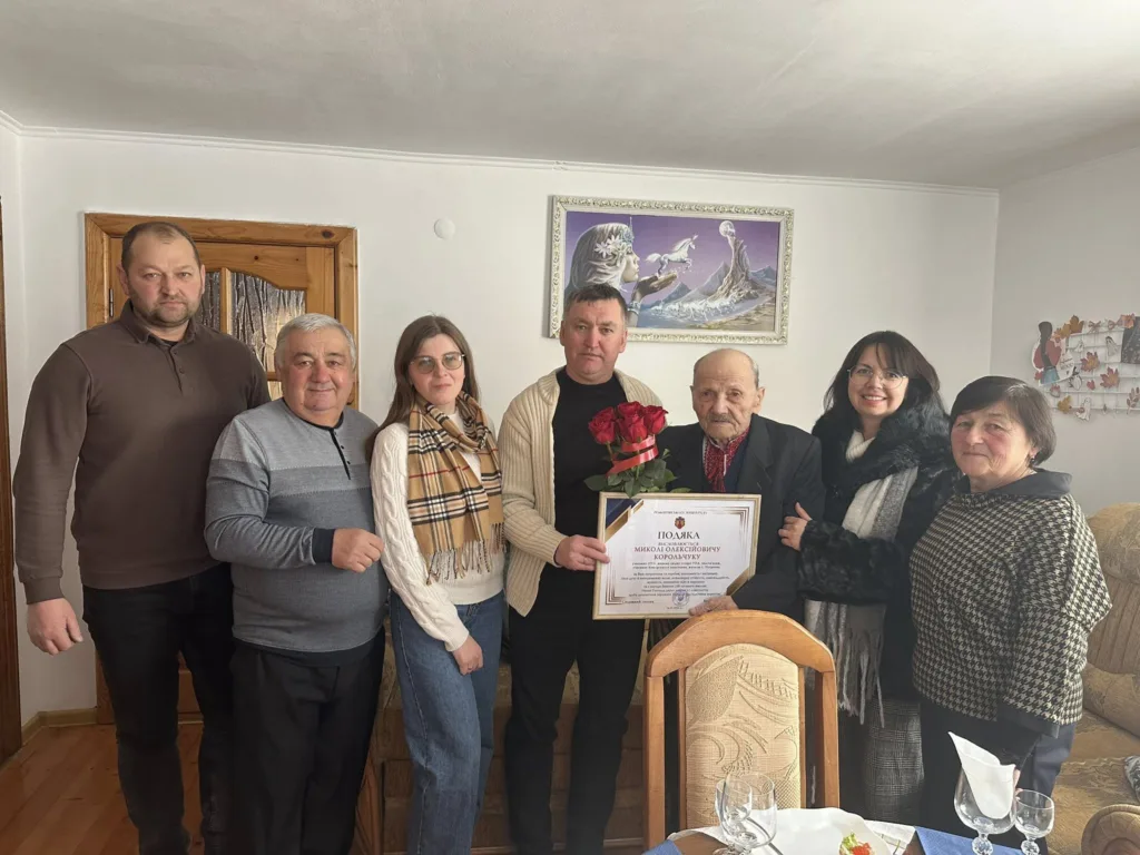 Група людей святкує вручення подяки літньому чоловікові