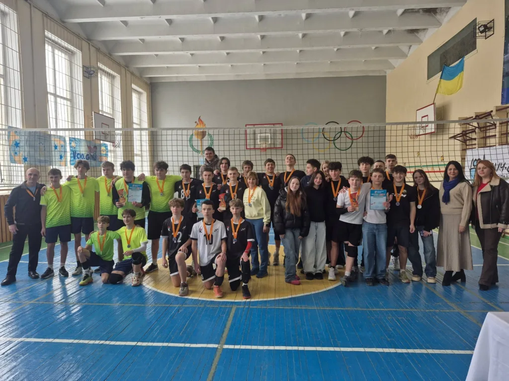 Шкільна волейбольна команда з медалями у спортивному залі