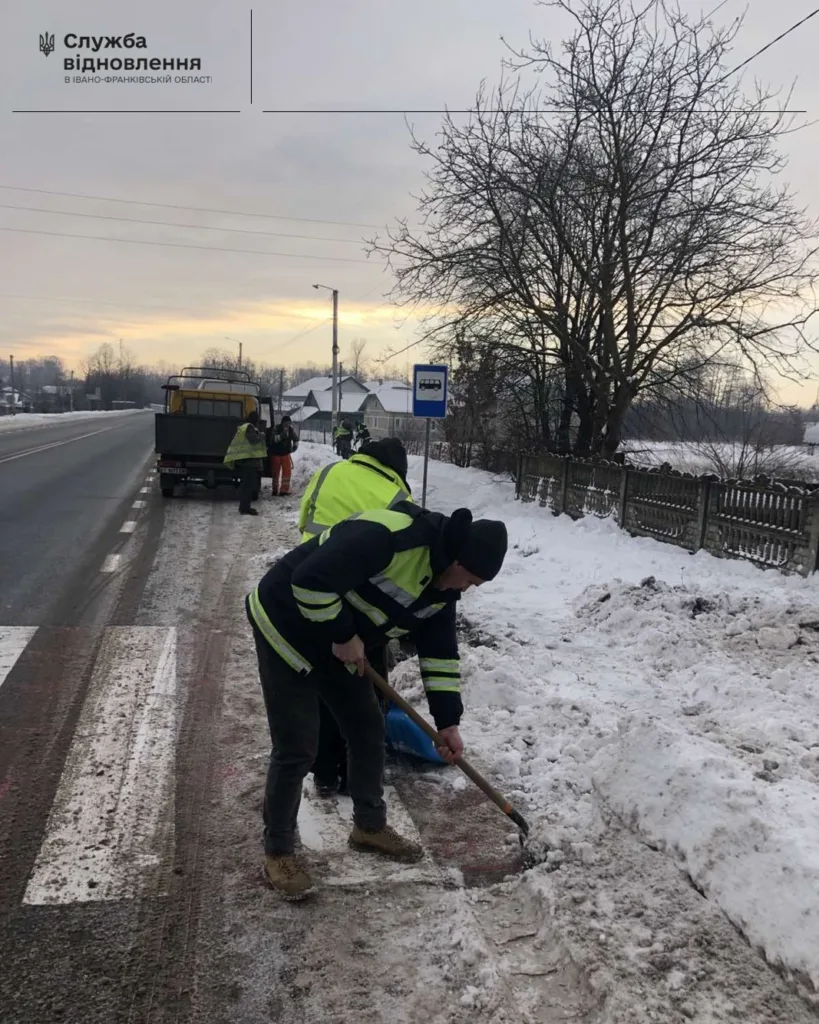 Робітники очищають сніг біля зупинки на дорозі
