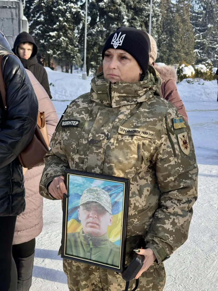 Волонтерка тримає фото українського військового на морозі