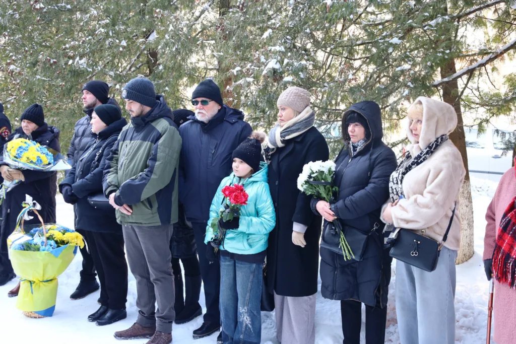 Люди з квітами на зимовій церемонії пам’яті