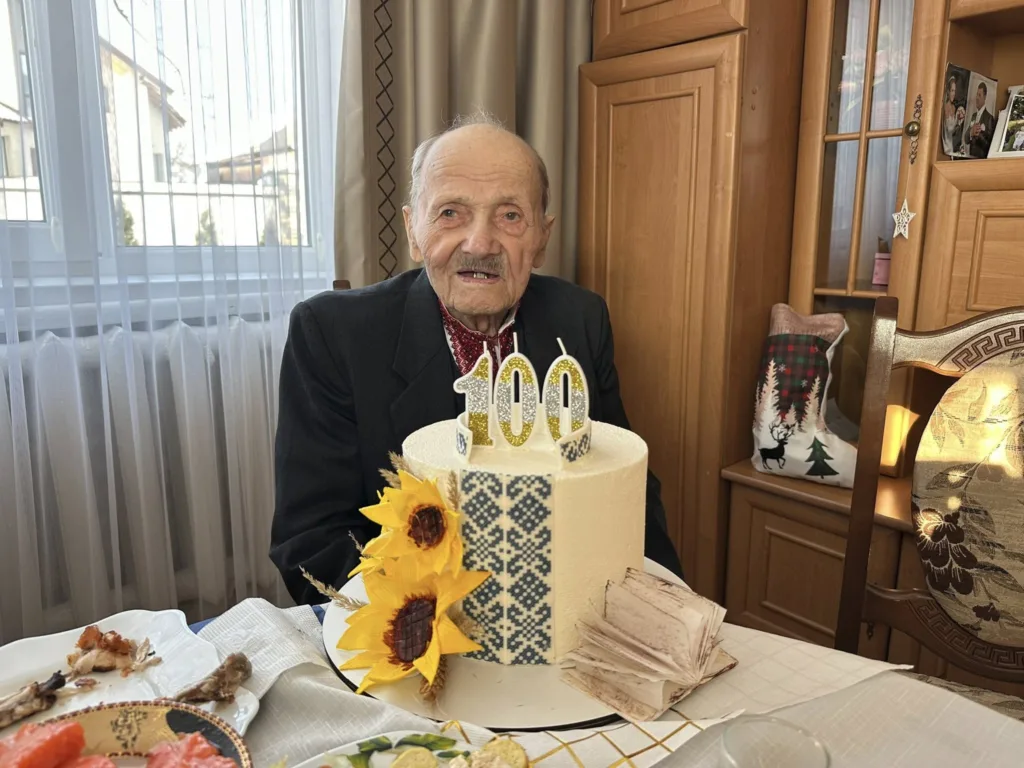 Дідусь святкує 100-річчя з тортом та свічками