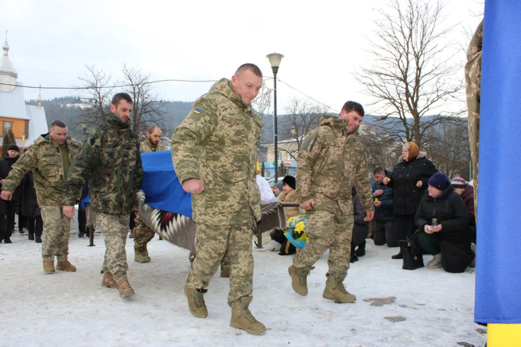 Військові несуть труну під українським прапором