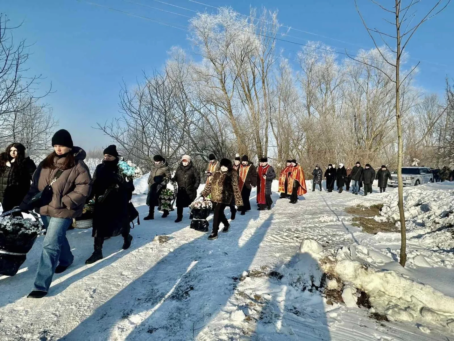 Похоронна процесія йде засніженою дорогою взимку