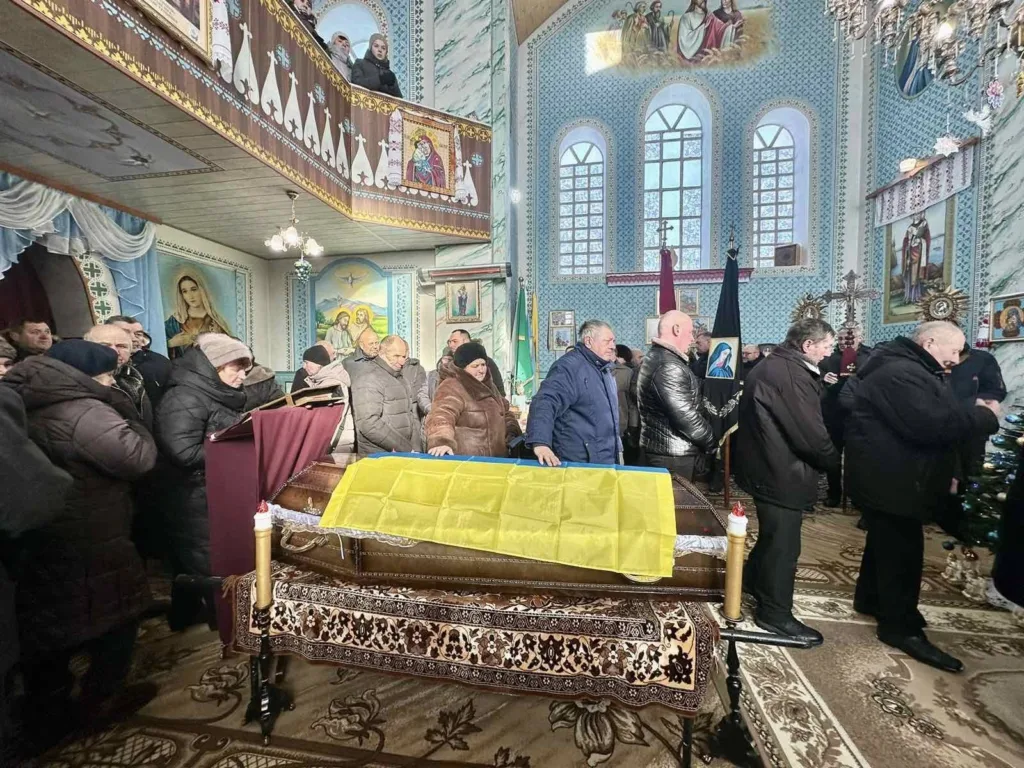 Прощання з померлим у церкві під українським прапором