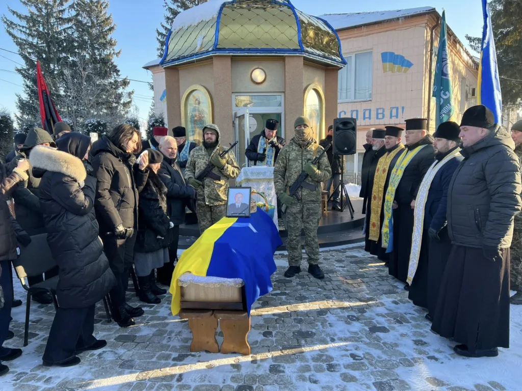 Похоронна церемонія з українським прапором і священниками