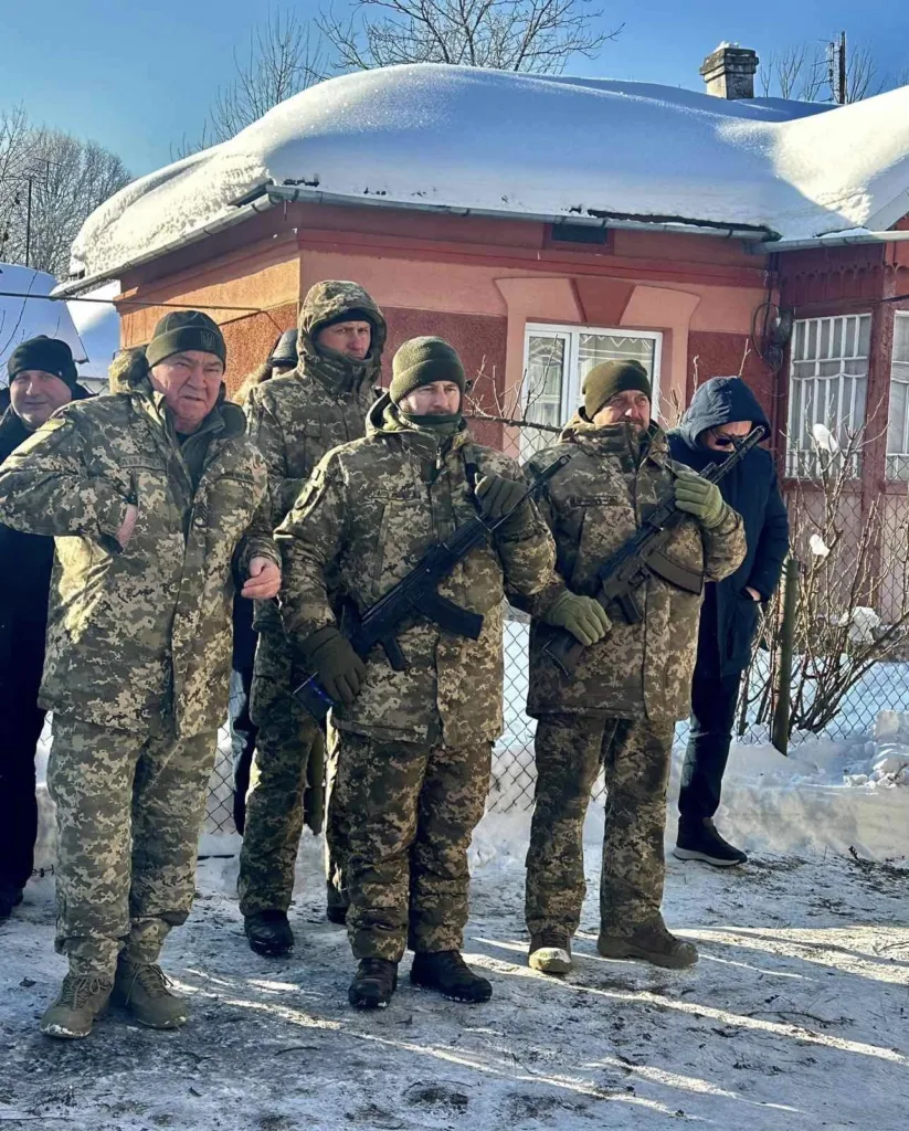 Українські військові стоять перед будинком взимку