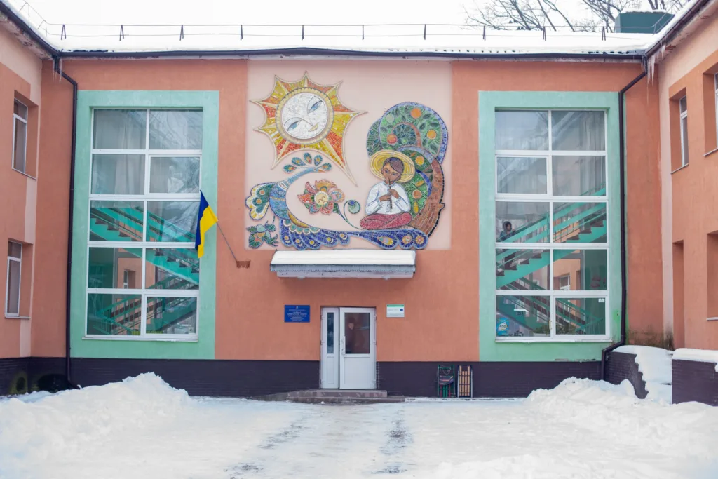 Будівля школи з мозаїкою та прапором України