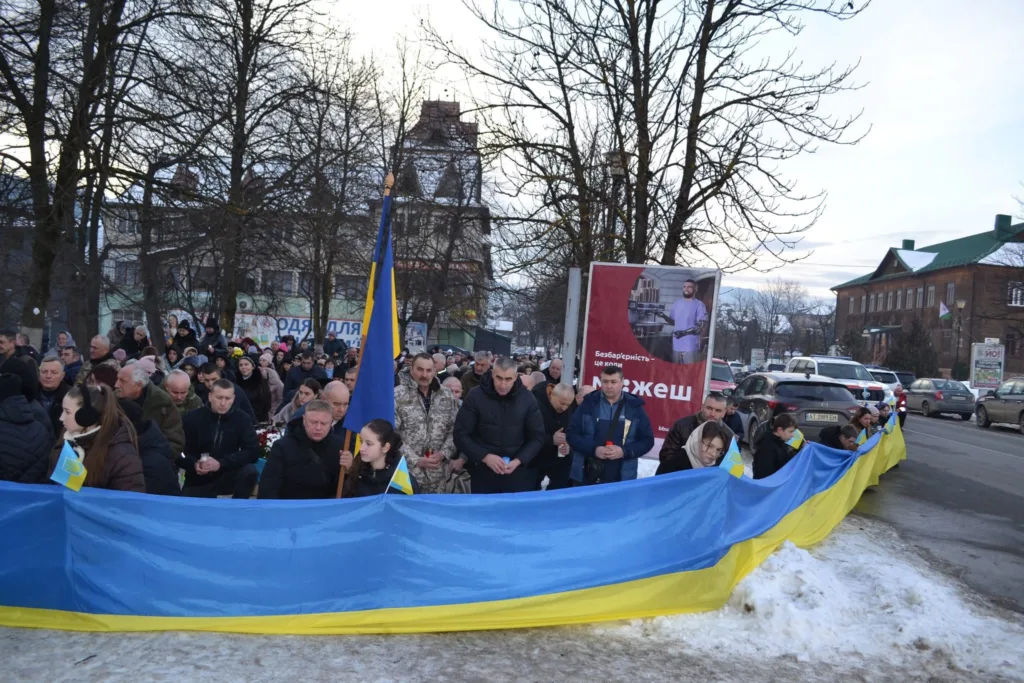 Люди з великим прапором України на вулиці