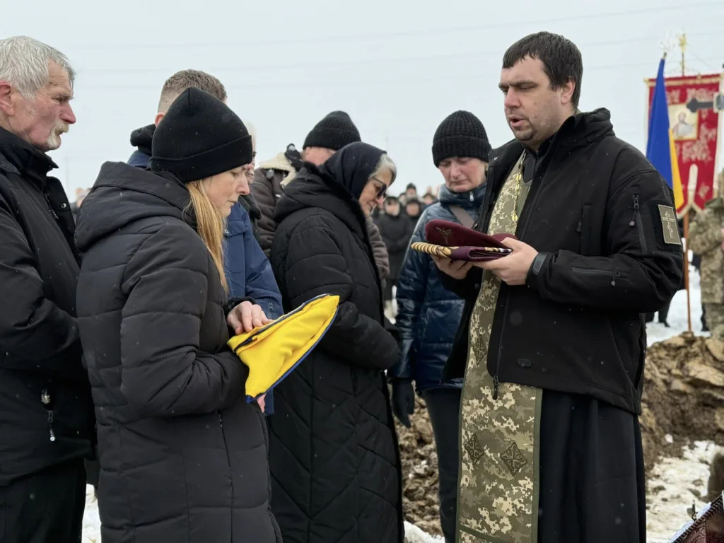 Священник і люди на церемонії поховання взимку
