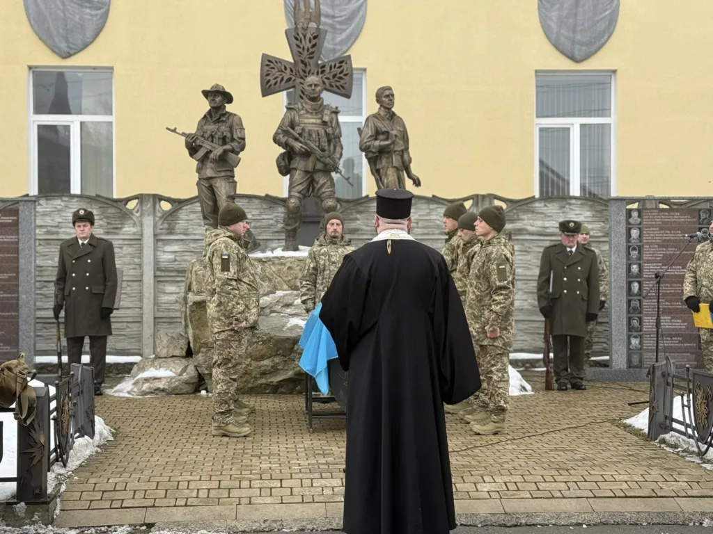 Військові та священник біля пам’ятника героям